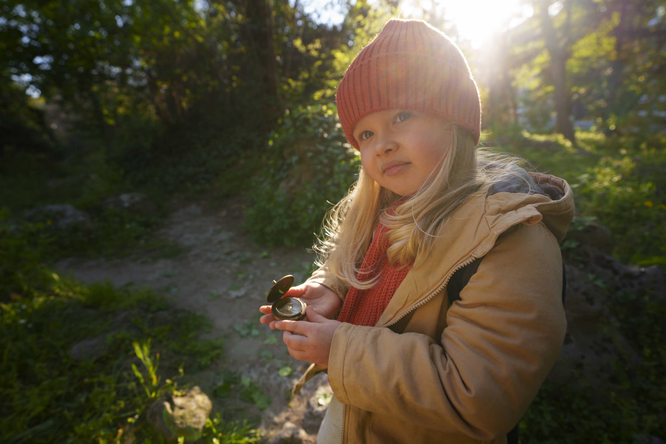 child outside in nature holding compass looking at camera